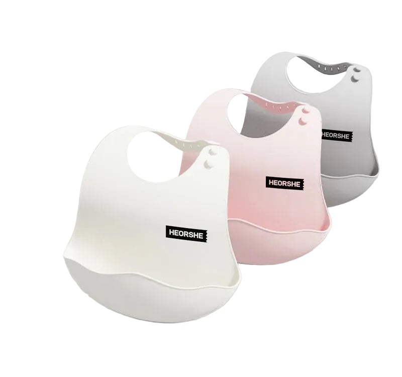Three baby bibs in white, pink, and gray with 'HEORSHE' branding on a light gray background.