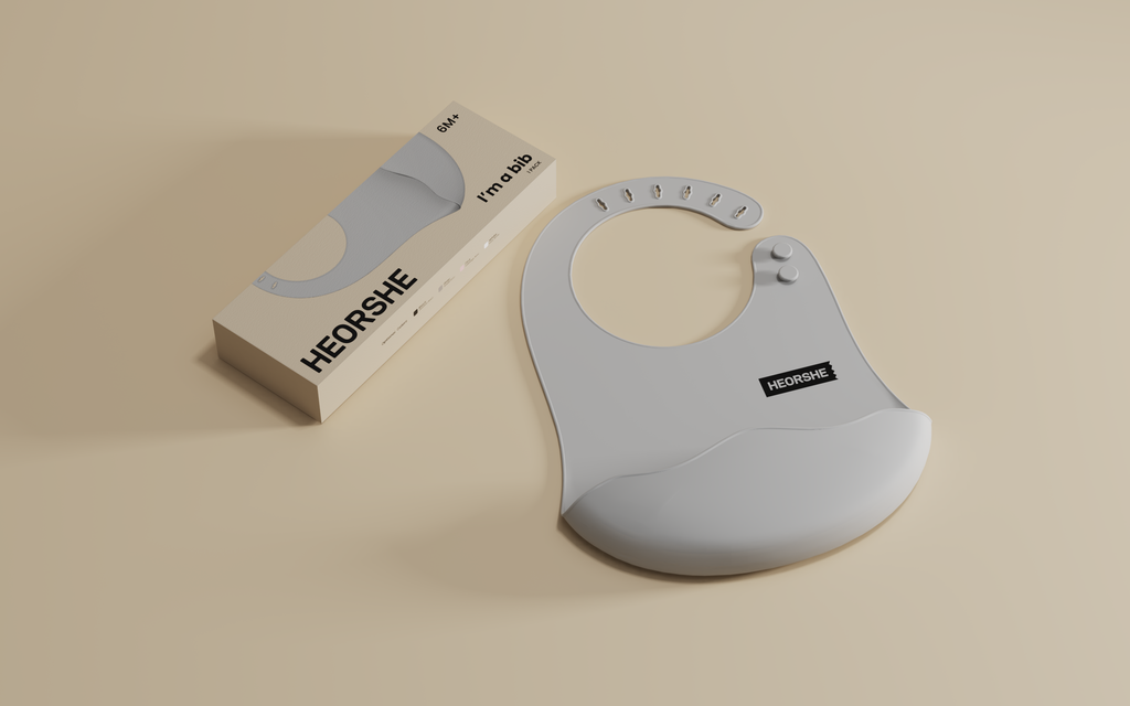 Gray baby bib with HEORSHE branding on a beige background
