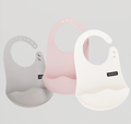 Three baby bibs in gray, pink, and white on a light gray background